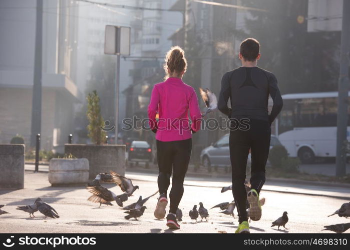 healthy young couple jogging in the city at early morning with sunrise in background