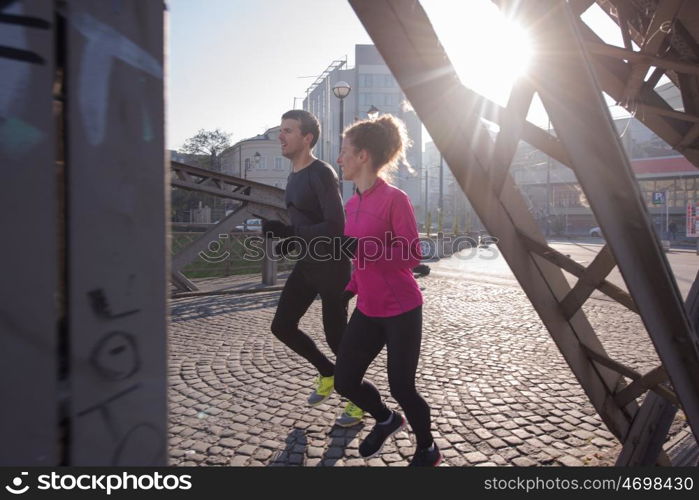 healthy young couple jogging in the city at early morning with sunrise in background