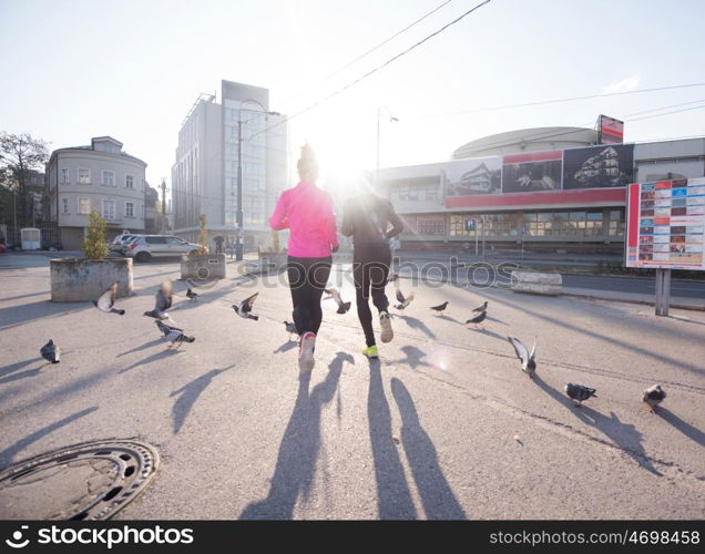 healthy young couple jogging in the city at early morning with sunrise in background