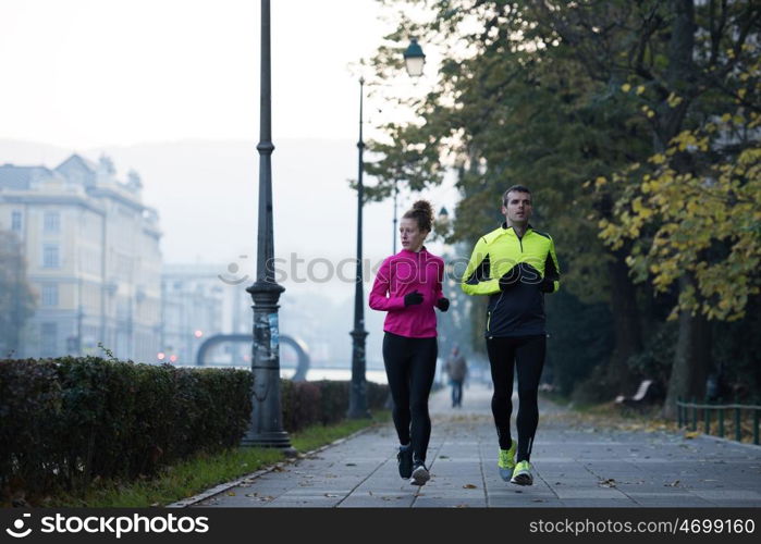 healthy young couple jogging in the city at early morning with sunrise in background