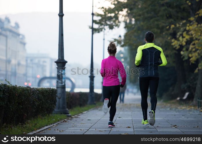 healthy young couple jogging in the city at early morning with sunrise in background