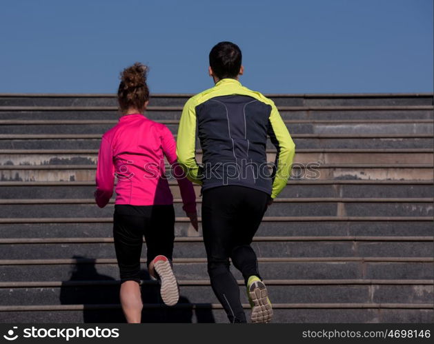 healthy young couple jogging on steps at early morning