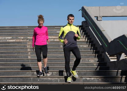 healthy young couple jogging on steps at early morning