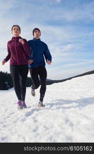 healthy young couple jogging outside on snow in forest. athlete running on beautiful sunny winter day