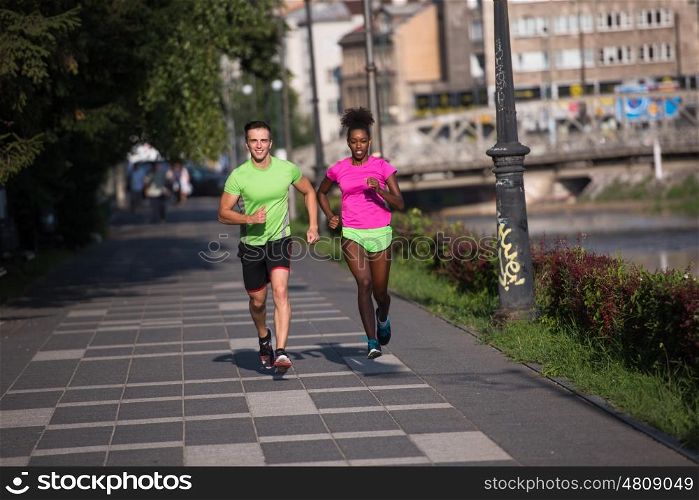 healthy young multiethnic couple jogging in the city on a sunny summer day