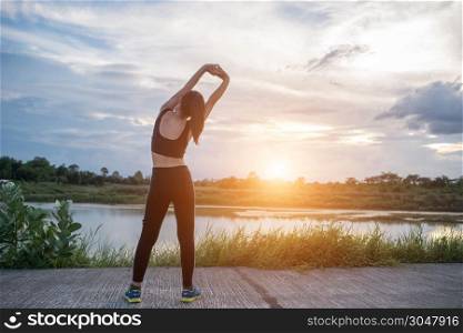 Healthy young woman warming up outdoors workout before training session at the park.