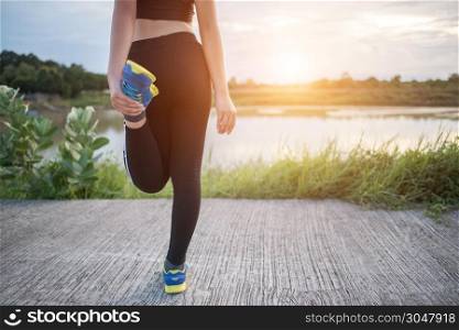 Healthy young woman warming up outdoors workout before training session at the park.