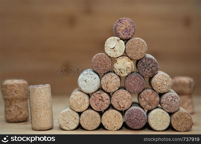 Heap of assorted wine corks on brick and wooden background.. wine corks stacked on each other in a triangle
