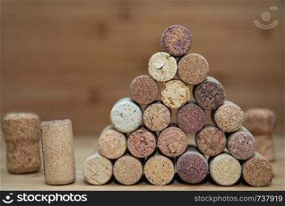 Heap of assorted wine corks on brick and wooden background.. wine corks stacked on each other in a triangle