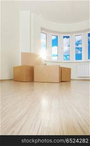 Heap of boxes in an empty living room against a window. Moving