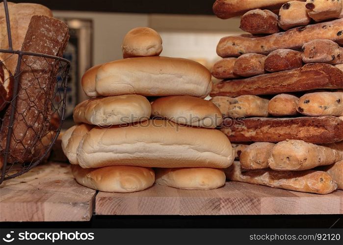 Heap of Bread Rolls Assortment and French Loaf on Wooden Board