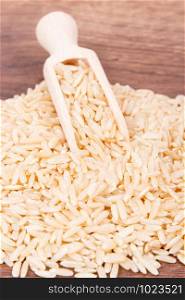 Heap of brown rice with wooden scoop, concept of healthy nutrition. Heap of brown rice with scoop, healthy nutrition
