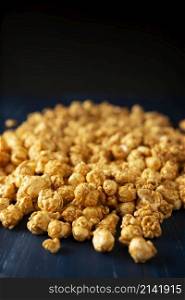 Heap of Caramel Corn on blue rustic table and black background with copy space for your text