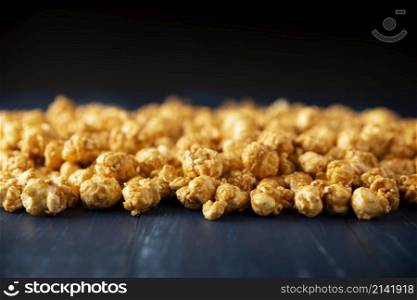 Heap of Caramel popcorn on blue rustic table and black background with copy space