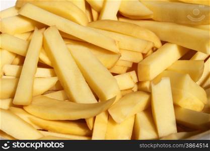 Heap of chopped pieces of raw potato strips for cooking potato chips, close-up, bright sinlight