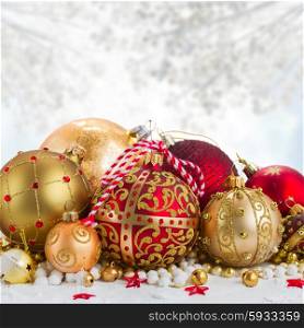 Heap of christmas balls in gold and red colors in snow on gray bokeh background. Pile of Christmas balls