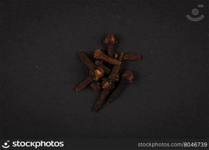 Heap of clove spice on dark stone plate background