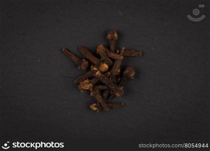 Heap of clove spice on dark stone plate background