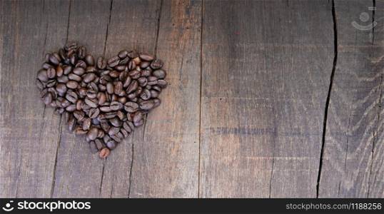 heap of coffee beans forming a heart on a rustic plank with copy sapce at the right