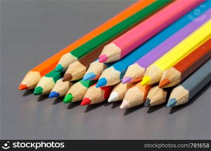 Heap of colored pencils on grey background