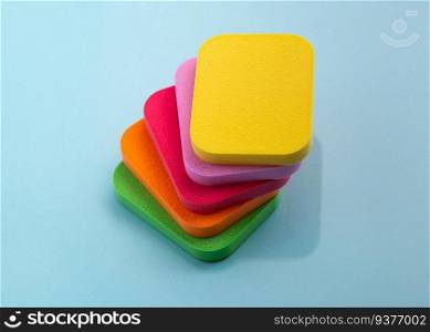 Heap of colorful cosmetic sponges on blue background. Top view. The heap of colorful cosmetic sponges on blue background. Top view
