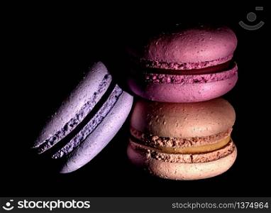 Heap of colorful macaroons on black background darkened. Heap of colorful macaroons darkened