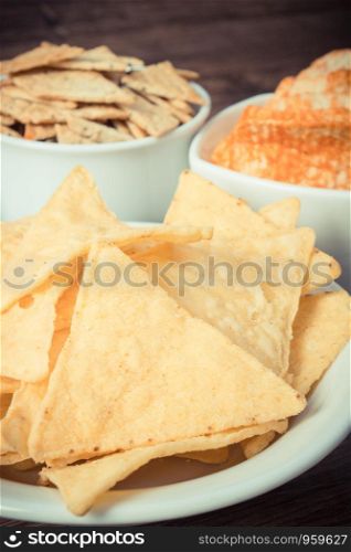 Heap of crunchy salted potato crisps and cookies in bowls, concept of restriction eating unhealthy food. Heap of crunchy salted crisps and cookies, concept of unhealthy food