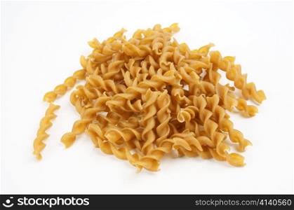 Heap of dark brown, organic, whole-grain noodles of spiral shape.