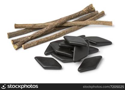 Heap of dried Licorice roots and black salt licorice confectionary, a Dutch treat, isolated on white background