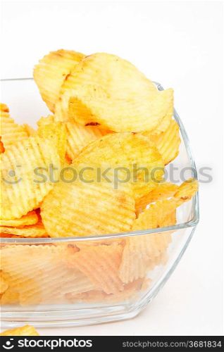 Heap of fried potato chips in glass bowl on white background.