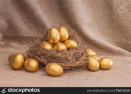 Heap of golden easter egg in nest on sack background