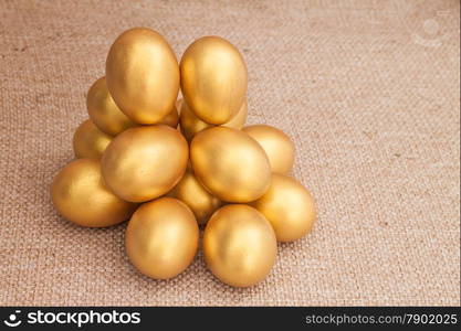 Heap of golden easter egg on brown sack background