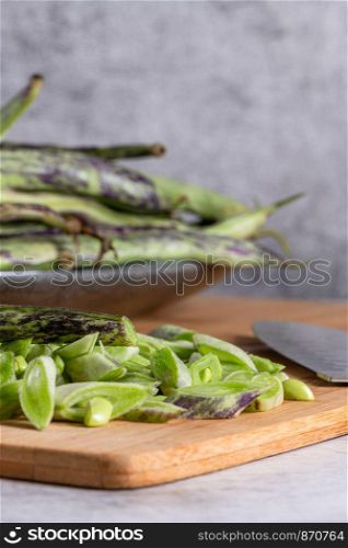 Heap of green beans on a rustic wooden table top view. Cutting board with green beans.