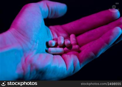 Heap of pills in hand closeup on dark background. Drugs tablets pile in palm.