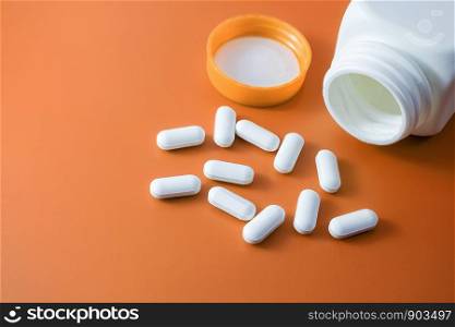 Heap of pills on orange background