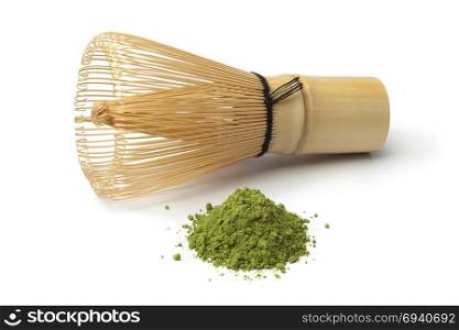 Heap of powdered green matcha tea and chasen on white background