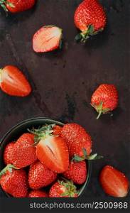 Heap of ripe strawberries in dark plate on old metal background with copy space. Top view point, vertical frame