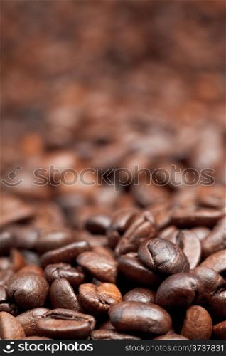 heap of roasted coffee beans background with focus foreground