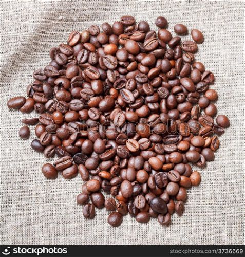 heap of roasted coffee beans on sackcloth close up