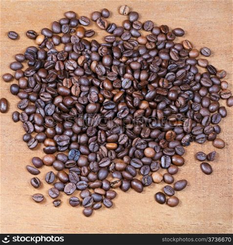 heap of roasted coffee beans on wooden board close up