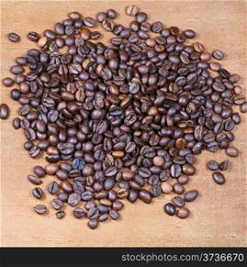 heap of roasted coffee beans on wooden board close up