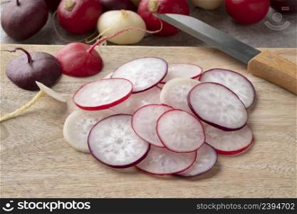 Heap of sliced fresh red, white and purple radish close up on a cutting board