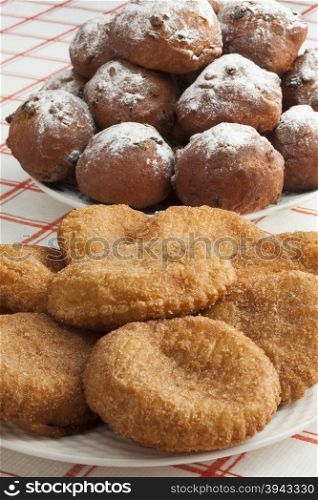Heap of sugared fried fritters called oliebollen and appelflappen on a dish
