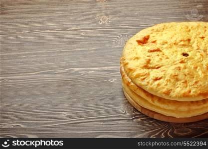 Heap of traditional Ossetian pies on wooden background.