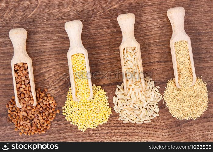 Heap of various groats, brown rice and quinoa seeds on rustic board, concept of healthy, gluten free food and nutrition. Heap of various groats, brown rice and quinoa seeds on board, healthy and gluten free food