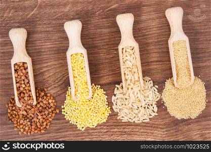 Heap of various groats, brown rice and quinoa seeds on rustic board, concept of healthy, gluten free food and nutrition. Heap of various groats, brown rice and quinoa seeds on board, healthy and gluten free food