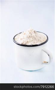 Heap of wheat flour in white vintage cup, selective focus