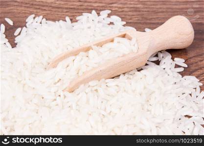 Heap of white rice with wooden scoop on rustic board, concept of healthy nutrition. White rice with wooden scoop on board, healthy nutrition