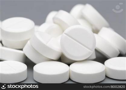 Heap of white round pills. Heap of white round pills on a gray background