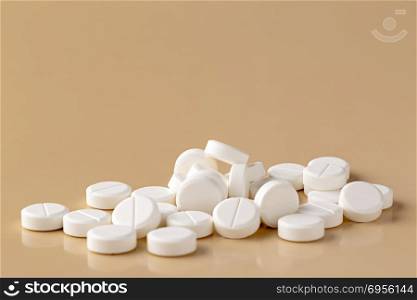 Heap of white round pills. Heap of white round pills on beige background